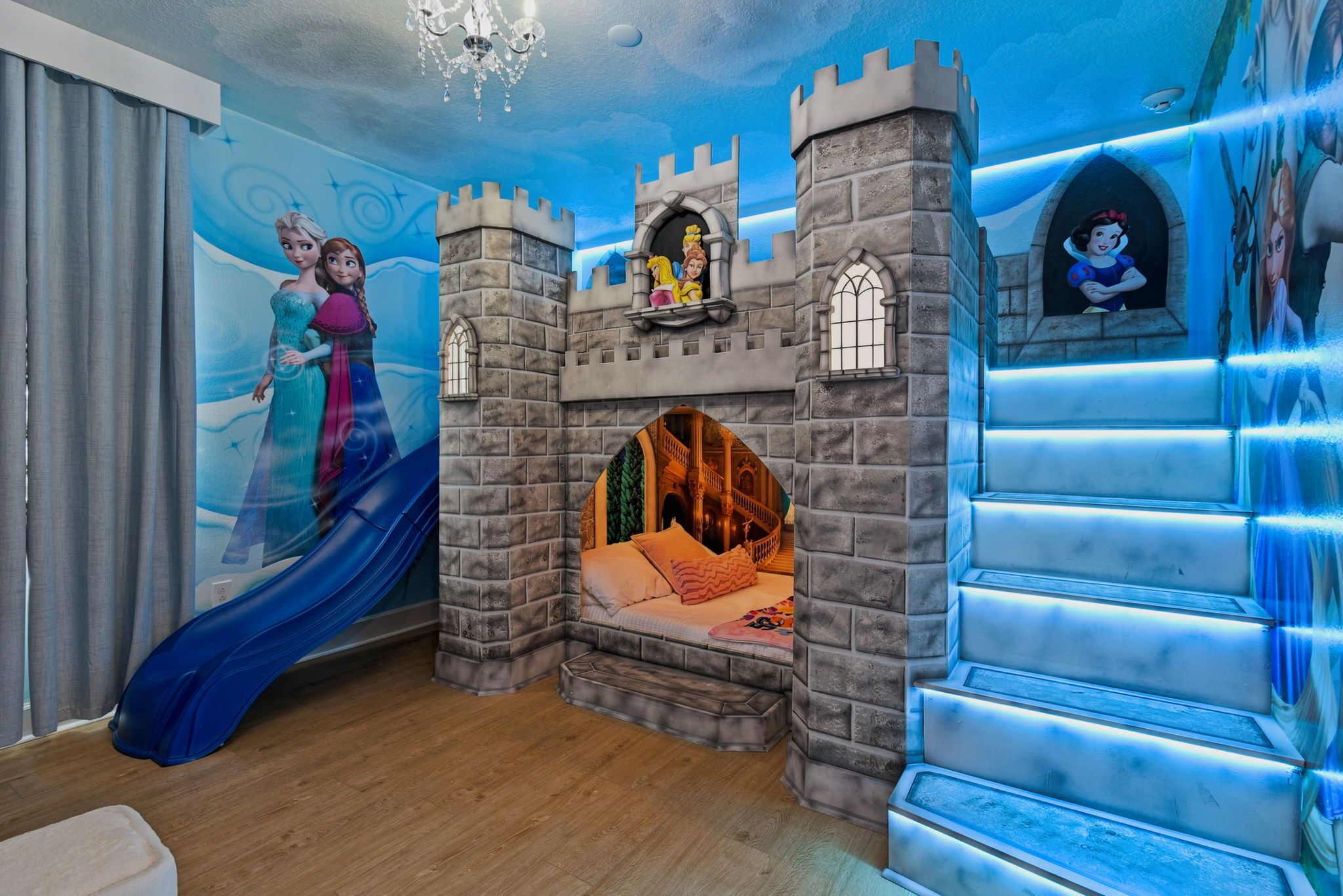 A room with a castle-themed bed, a slide, and a mural with animated characters.