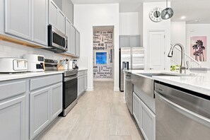 Una cocina moderna con armarios grises, electrodomésticos de acero inoxidable y una isla central.
