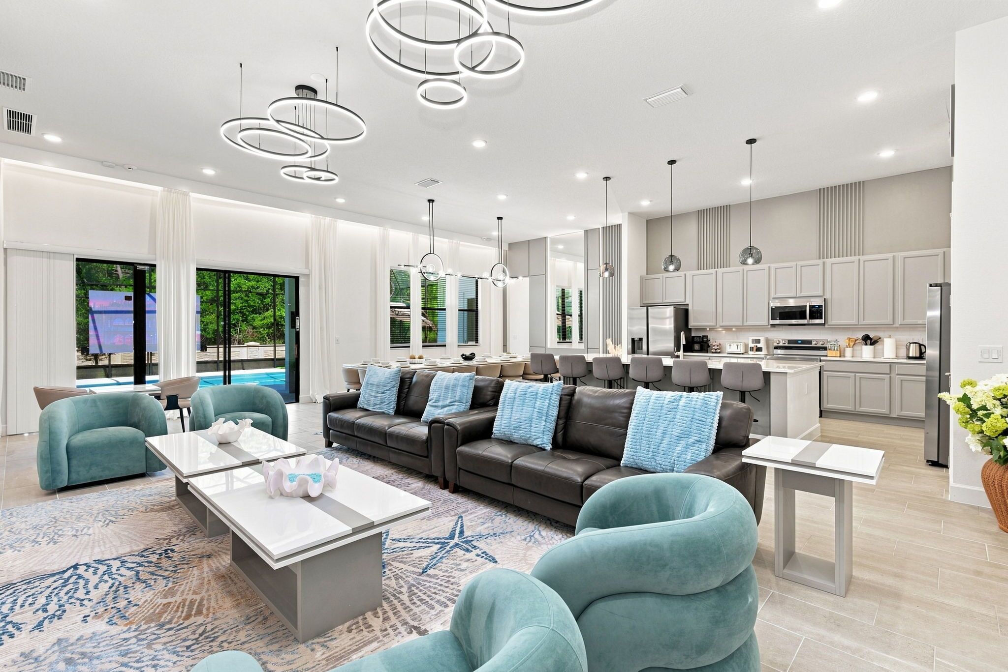 A modern living room with a sofa, chairs, a coffee table, and a kitchen area with cabinets and appliances.