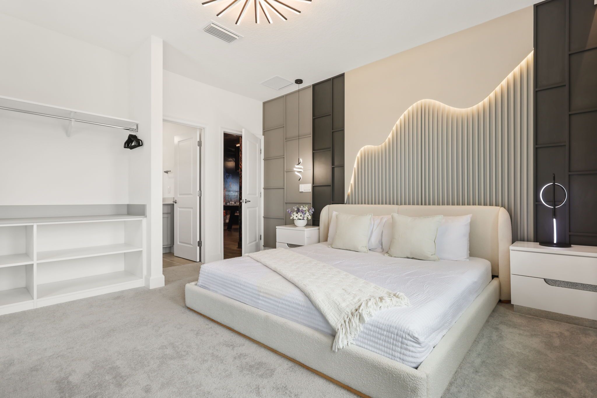 Une chambre à coucher moderne avec un grand lit, des tables de chevet, une armoire et un banc intégré.