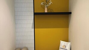 Habitació amb un sofà, una taula, un ram de flors decoratiu i un coixí amb la inscripció 'RUMAVALET'.