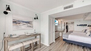 A bedroom with a bed, bedside tables, a desk with a chair, a painting on the wall, and a sign for 'BIG FISH'. - Direct Oceanfront  Amazing Views In Camelot Resort (Myrtle Beach)