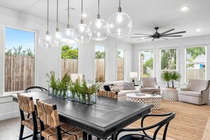 A modern dining area with a wooden table, chairs, and hanging pendant lights. - Coastal Retreat - Private Pool - Easy Beach Access (Panama City Beach)