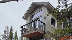A multi-story house with a stone foundation, a balcony, and a mountain logo on the wall. - Colorado Mountain Retreat - A peaceful Lake View Cabin with Amazing Views! (Idaho Springs)