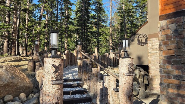 A wooden staircase leading up to a building with a stone wall and a logo that reads 'Welcome to the Forest.' - Colorado Mountain Retreat - A peaceful Lake View Cabin with Amazing Views! (Idaho Springs)
