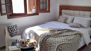 Ein Schlafzimmer mit einem Bett, einem Nachttisch mit Essensservitau und einem Stuhl, sowie einem Fenster mit Rollläden.