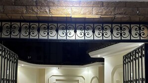 Ein Korridor mit einer Steinwand, einem schmiedeeisernen Geländer und einer Deckenleuchte.