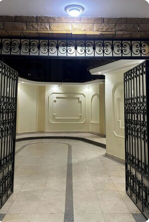 A hallway with a stone wall, a decorative metal gate, and a light fixture on the ceiling. - Prime Location with Stunning View: Opposite the Museum of Egyptian Civilization, (Fustat)