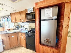 Une cuisine avec des meubles de rangement en bois, un four à micro-ondes, une cuisinière et un réfrigérateur.