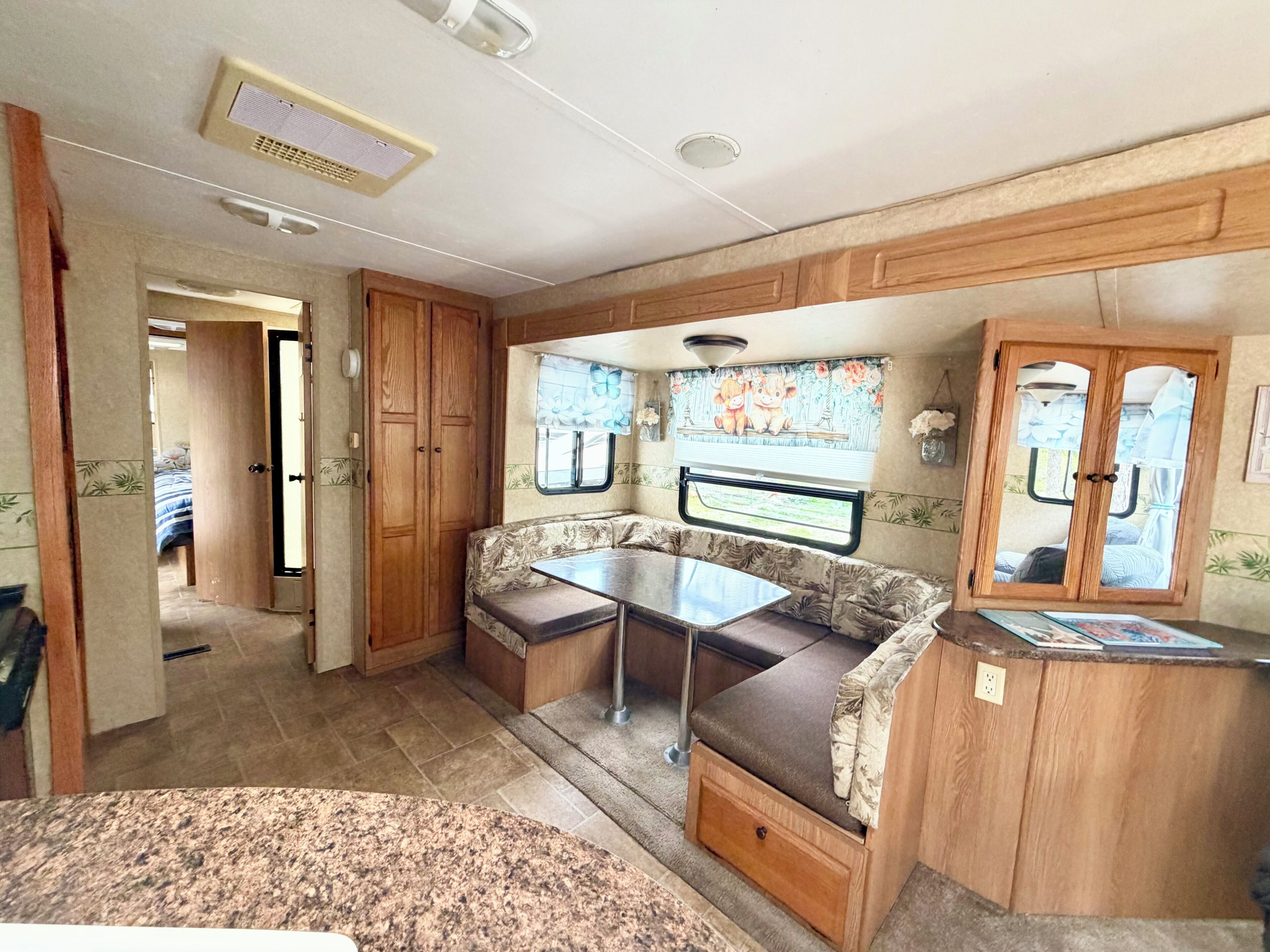A compact RV interior with a kitchenette, a dining area, and a sleeping space.