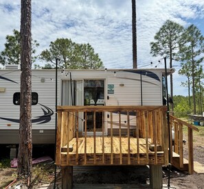 Une maison mobile dotée d’une terrasse en bois et d’une pancarte sur laquelle on peut lire : « Bienvenue au paradis ».
