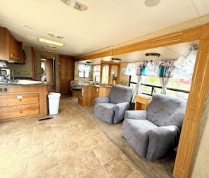 Un intérieur de camping-car compact comprenant un coin cuisine, deux espaces salon et une petite table.