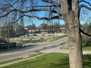 Eine straßenübergreifende Kreuzung mit Bäumen, einer Straße, Gebäuden und einem Parkplatz im Hintergrund.