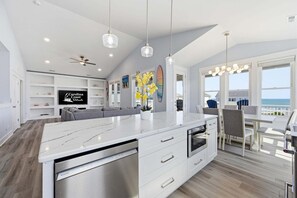 A modern kitchen with a large island, white cabinetry, and a view of the ocean. - Blue Dolphin: Oceanview, game room and Grill (North Topsail Beach)