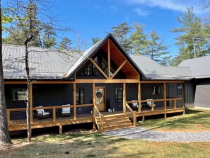 Eine Holzhütte mit überdachter Veranda, einer Holztreppe und einem großen Fenster.
