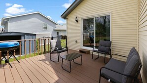 Une terrasse dotée de mobilier d’extérieur, d’un barbecue et d’une porte-fenêtre coulissante donnant sur la maison.