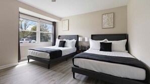 Une chambre avec deux lits, un ventilateur de plafond et une grande fenêtre.