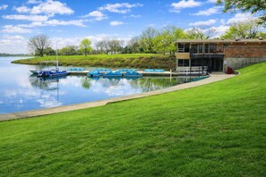 A lakeside building with a pool, boats, and a grassy area. - O’Hare 7-Bed Home | Workers & Insurance (Des Plaines)