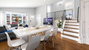Een moderne woonkamer met een eetgedeelte, een trap en uitzicht op buiten.