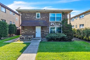 A two-story brick building with a white door, a small porch, and a stone accent wall. - Westchester Corporate Stay 5 Beds (Westchester)