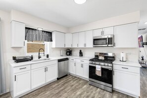 A modern kitchen with white cabinetry, a stainless steel stove, a microwave, and a dishwasher. - Westchester Corporate Stay 5 Beds (Westchester)