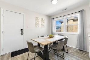 A dining area with a table, chairs, a window with curtains, and artwork on the wall. - Westchester Corporate Stay 5 Beds (Westchester)