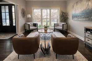A living room with two leather armchairs, a coffee table, a lamp, and a painting on the wall. - Luxury Executive Retreat | Gym & Dual Office (Crystal Lake)