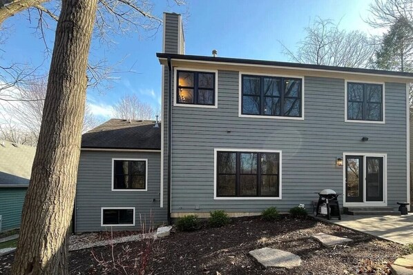 A two-story house with a gray exterior, multiple windows, and a chimney. - Luxury Executive Retreat | Gym & Dual Office (Crystal Lake)