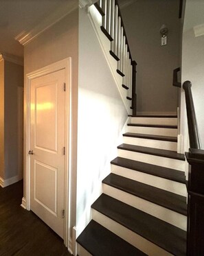 A staircase with a black and white design, a white door, and a light switch on the wall. - Luxury Executive Retreat | Gym & Dual Office (Crystal Lake)