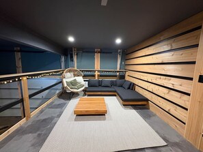Un intérieur moderne avec un canapé d’angle, un banc en bois et un fauteuil suspendu.