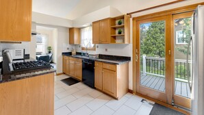 A modern kitchen with wooden cabinets, a black stove, and a dishwasher. - Family Haven in Streamwood | Ideal for Stay Long (Streamwood)
