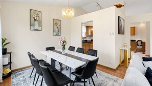 A dining area with a marble table, black chairs, a chandelier, and framed artwork on the walls. - Family Haven in Streamwood | Ideal for Stay Long (Streamwood)
