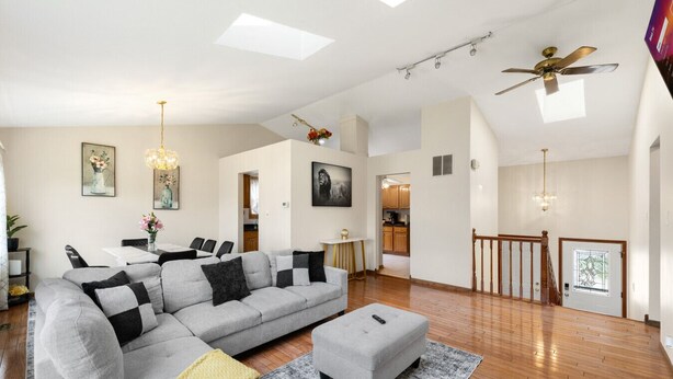 A spacious living room with a large gray sofa, a small ottoman, and a dining area with a table and chairs. - Family Haven in Streamwood | Ideal for Stay Long (Streamwood)