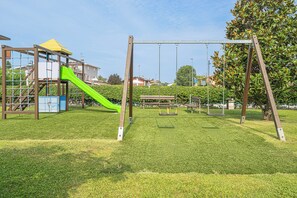 Un'area giochi con scivolo, altalene e struttura per arrampicata.
