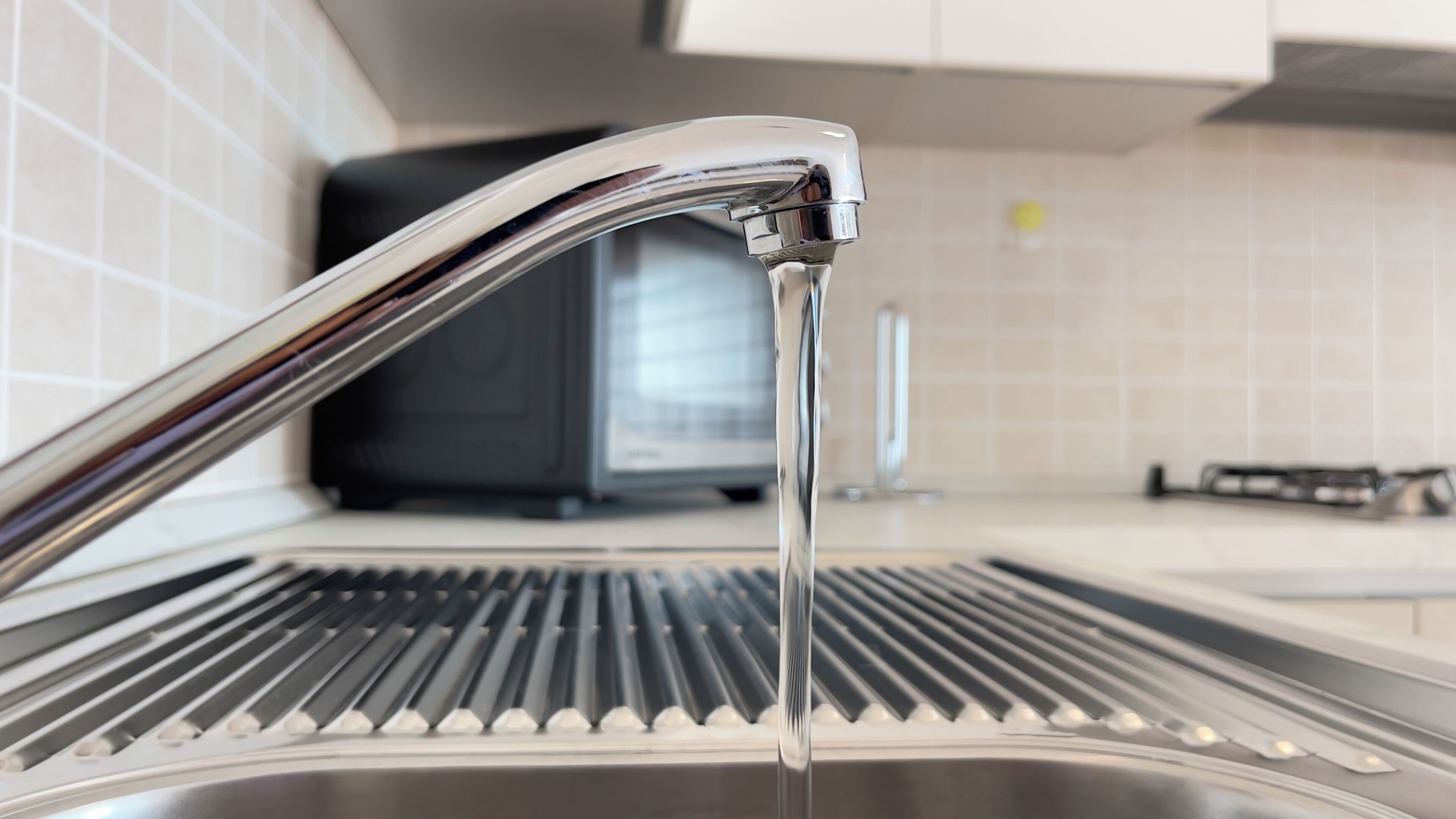 Un évier de cuisine avec l’eau courante, un robinet moderne et un plan de travail en acier inoxydable.