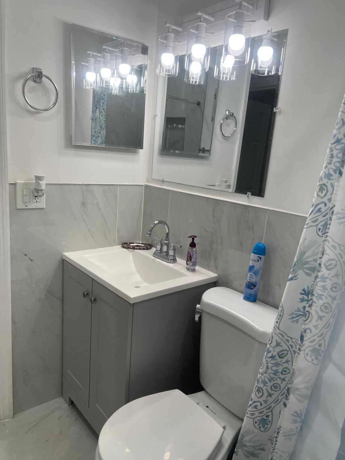 A bathroom with a sink, mirror, toilet, and shower curtain.