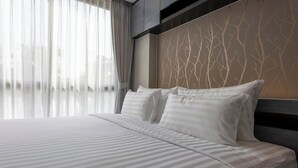 A modern hotel room with a large bed, sheer curtains, and a wall with a tree branch pattern. - 60sqm Pool Access Suite in Patong w/ Views C81 (Pataong)