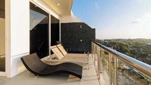 A balcony with a black textured wall, a glass railing, and a lounge chair. - 60sqm Pool Access Suite in Patong w/ Views C81 (Pataong)