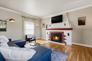Ein Wohnzimmer mit Kamin, einer Couch, einem Sessel und einem Fernseher.