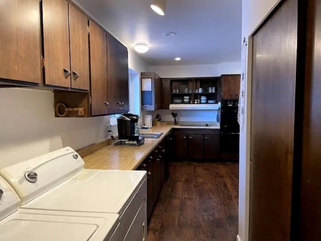 A compact kitchen with wooden cabinets, a white washing machine, and a black refrigerator.