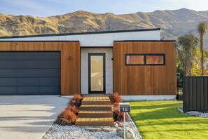 Ein modernes, zweistöckiges Haus mit Garage, Holzverkleidung und der Hausnummer 16.