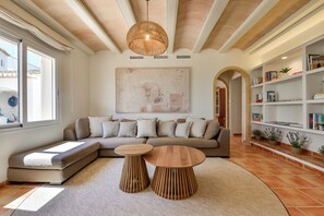 Ein modernes Wohnzimmer mit einem Ecksofa, zwei Holztischen, einem großen abstrakten Gemälde und einem Bücherregal.