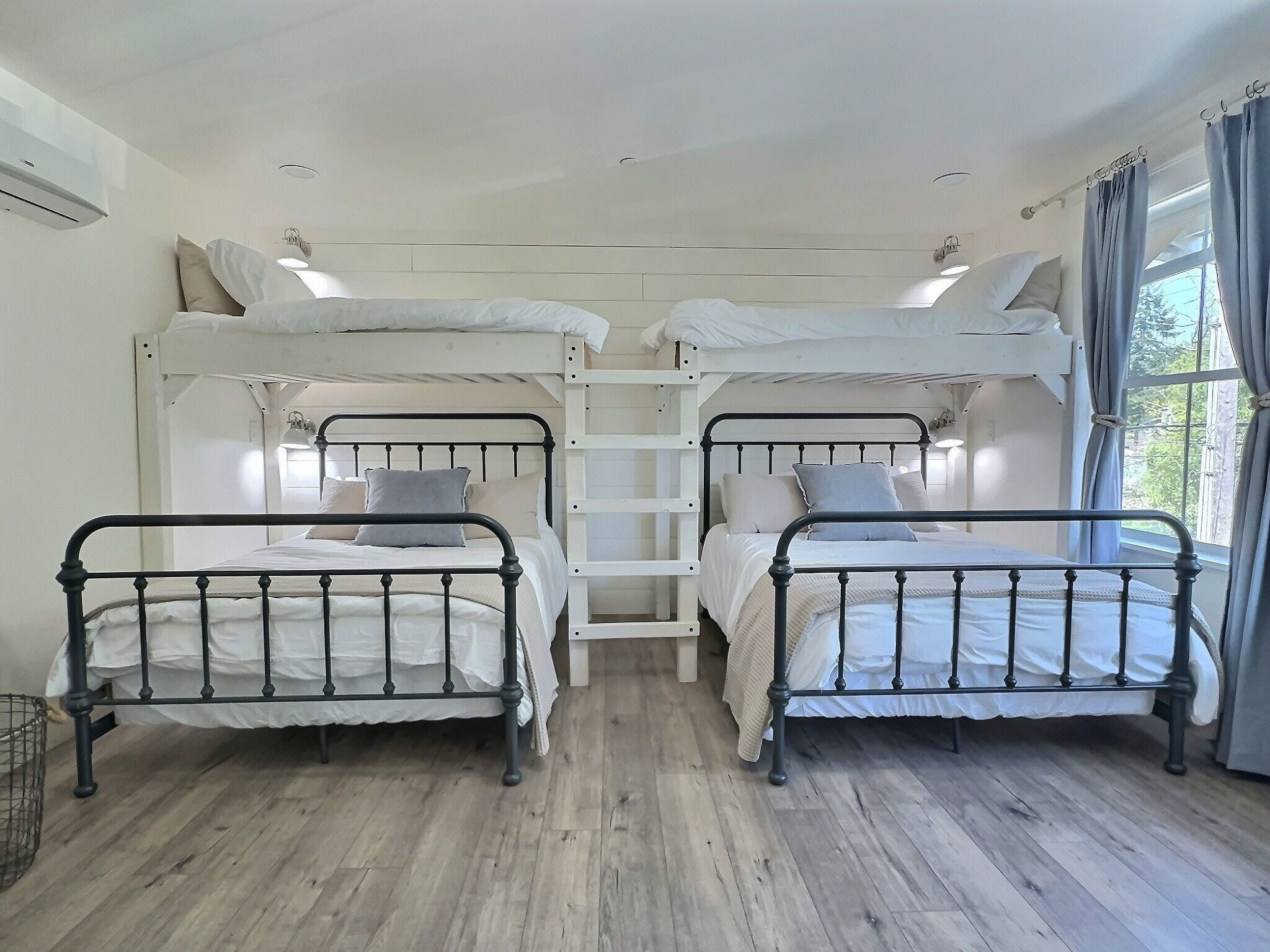 Une chambre avec deux lits superposés, une échelle et une fenêtre avec des rideaux.