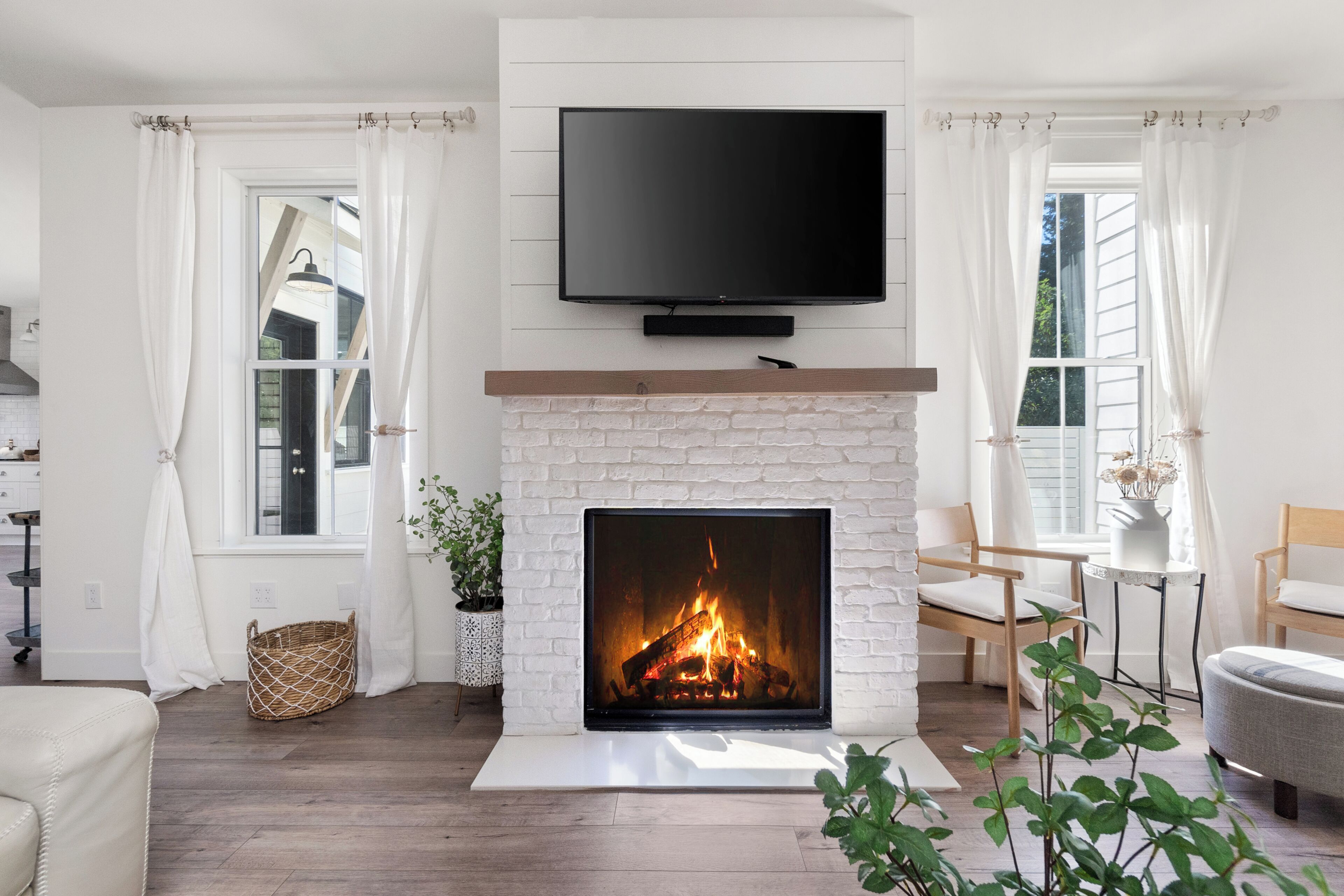 A living room with a fireplace, a flat-screen TV mounted above it, and a window with curtains.