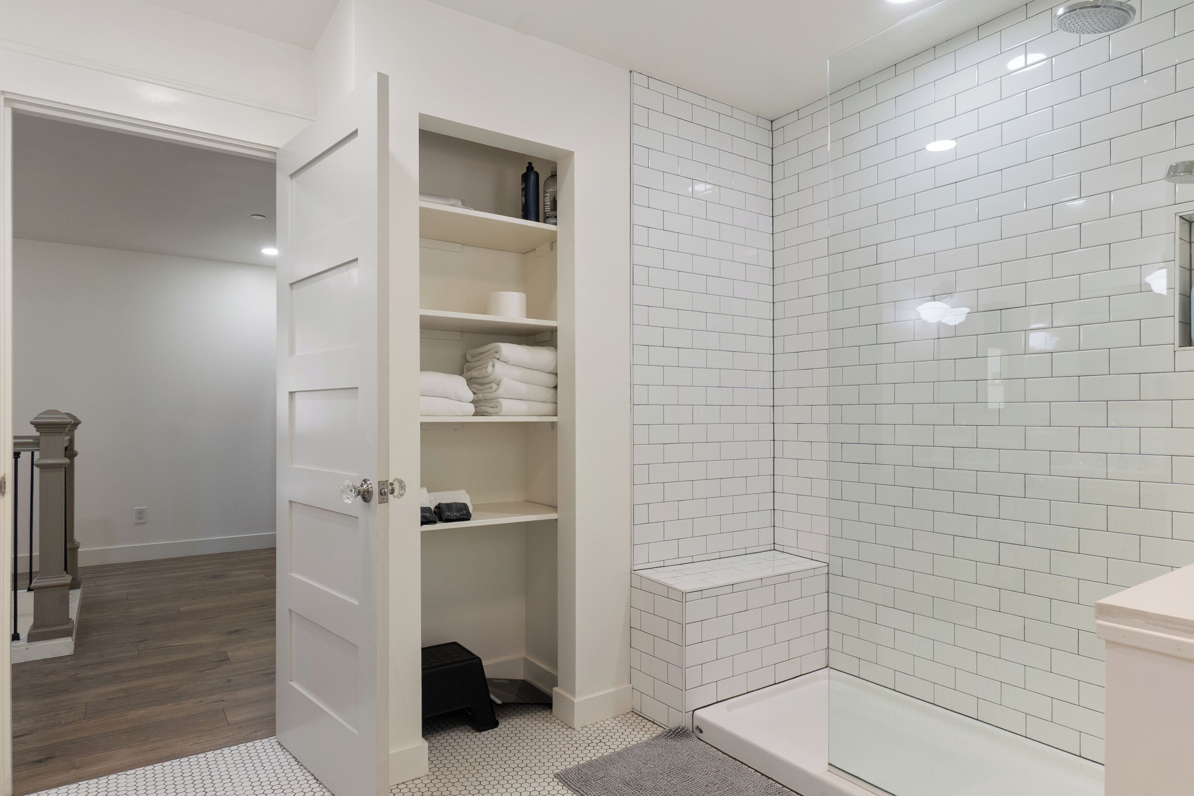 Une salle de bain avec des murs carrelés de carrelage blanc, une douche, des toilettes et un meuble de rangement.
