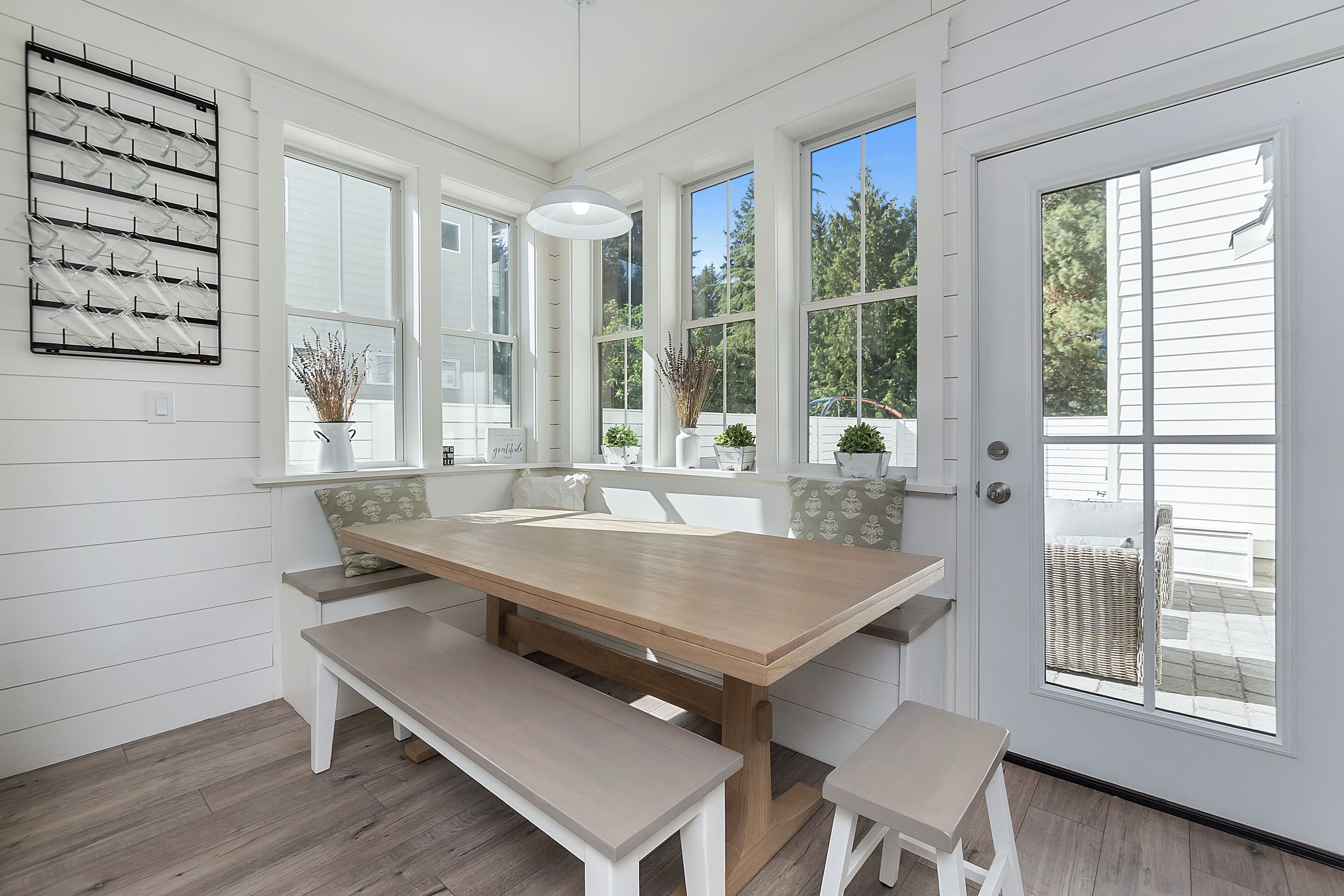 A dining area with a wooden table, benches, and large windows.