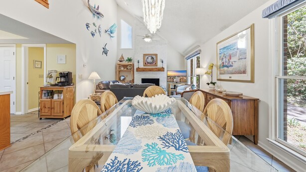 Un comedor con una mesa de vidrio, sillas de madera y un mantel decorativo.
