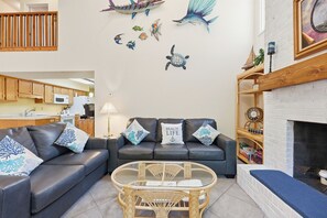 Ein Wohnzimmer mit einer Couch, einem Glastisch und einem Kamin.