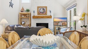 Una sala de estar con chimenea, una mesa de comedor con sillas, un sofá y objetos decorativos.