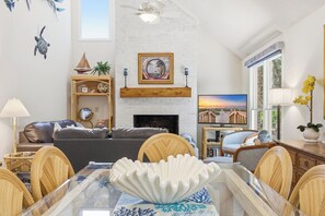 Ein Wohnzimmer mit Kamin, einem Esstisch mit Stühlen, einer Couch und Dekorationselementen.